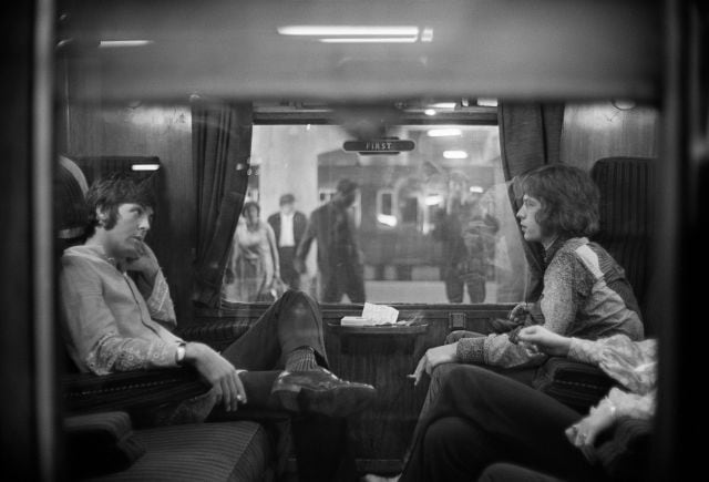 Paul McCartney y Mick Jagger, sentados frente a frente en un tren en Euston Station, en 1967.