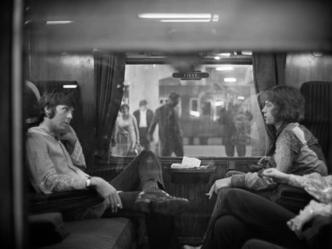 Paul McCartney y Mick Jagger, sentados frente a frente en un tren en Euston Station, en 1967.