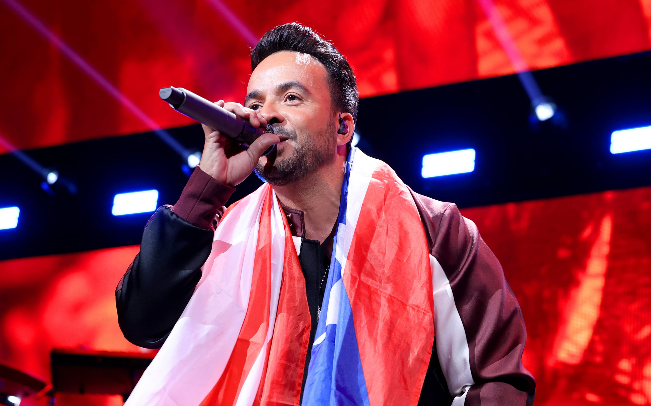 Luis Fonsi cantando con la bandera de Puerto Rico al cuello