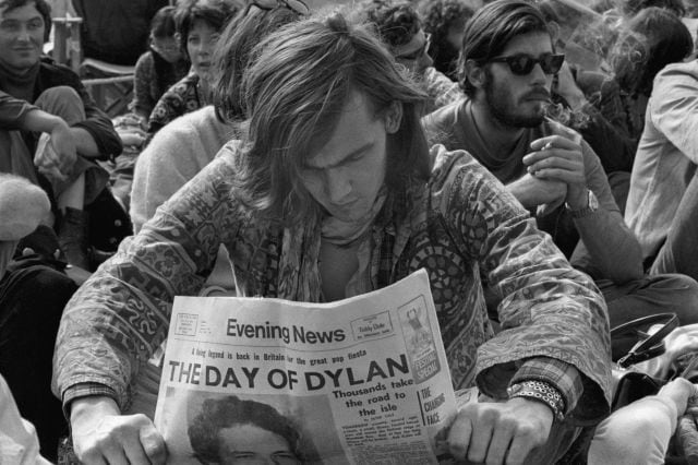 Un hombre lee el periódico con una fotografía de Bob Dylan en el Festival de la Isla de Wight en 1969.