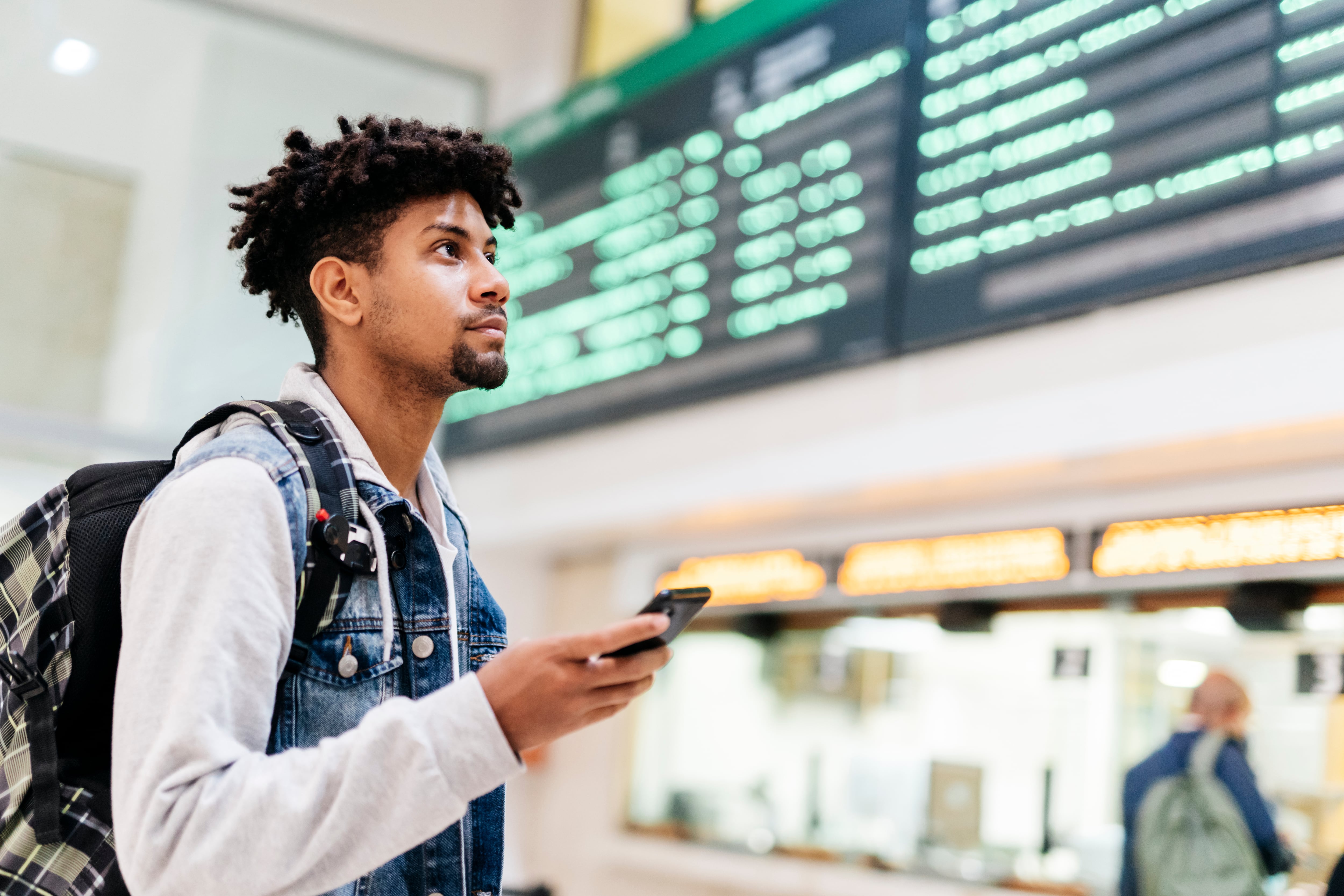 Un joven en el aeropuerto mirando la lista de destinos