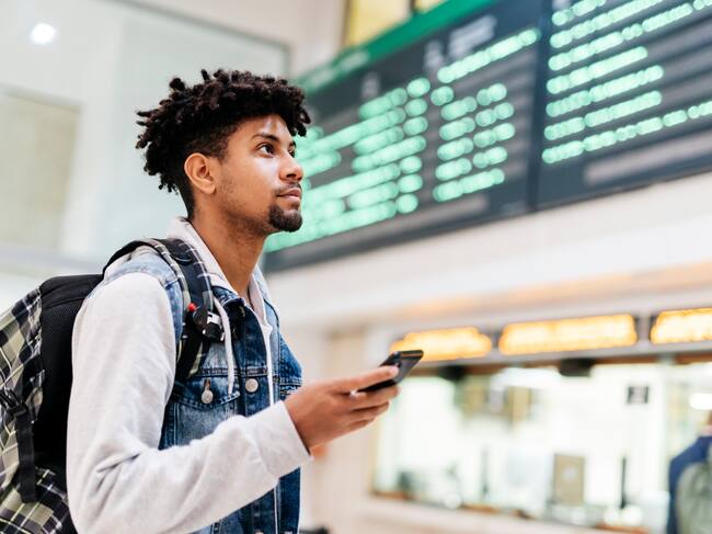 Un joven en el aeropuerto mirando la lista de destinos