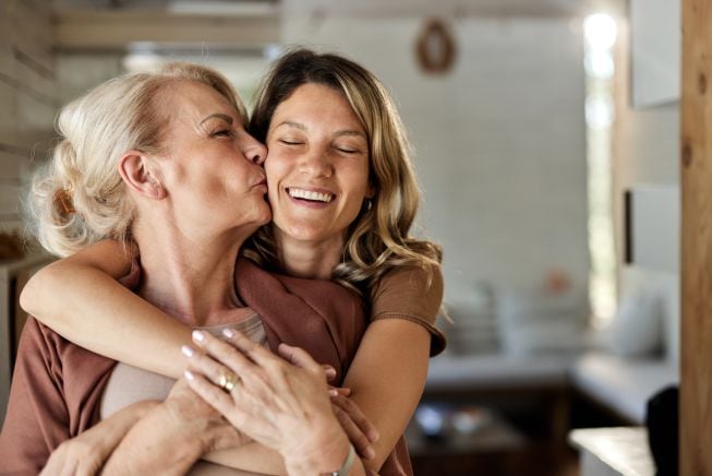 Madre e hija dándose un beso y un abrazo.