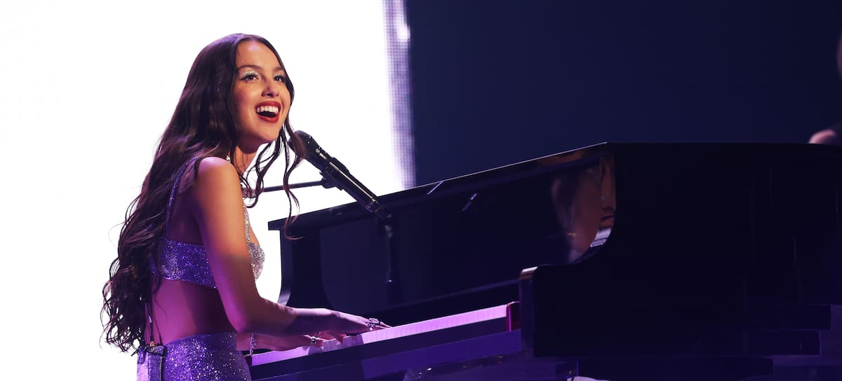 Olivia Rodrigo sobre el escenario, vistiendo un conjunto de top y falda plateado, interpretando una de sus canciones en el GUTS Tour de 2024.