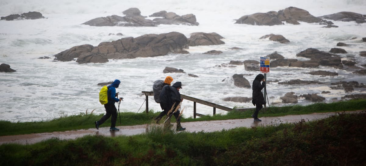 Unos peregrinos recorren el Camino de Santiago durante una tormenta.