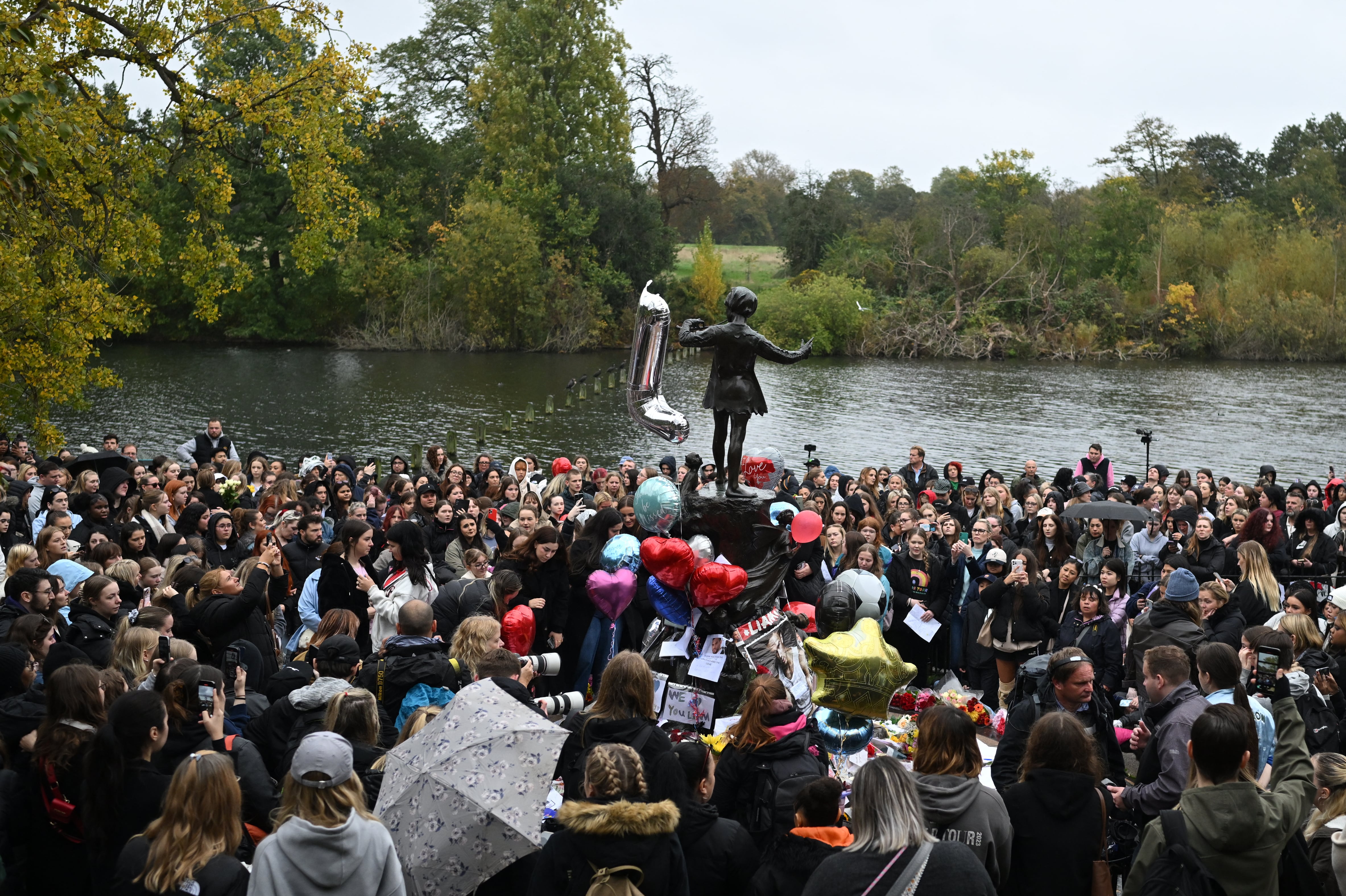 Fans del cantante Liam Payne con globos y flores junto a la estatua de Peter Pan en el parque de Hyde Park en Londres el 20 de octubre de 2024. (Photo by JUSTIN TALLIS / AFP) (Photo by JUSTIN TALLIS/AFP via Getty Images)