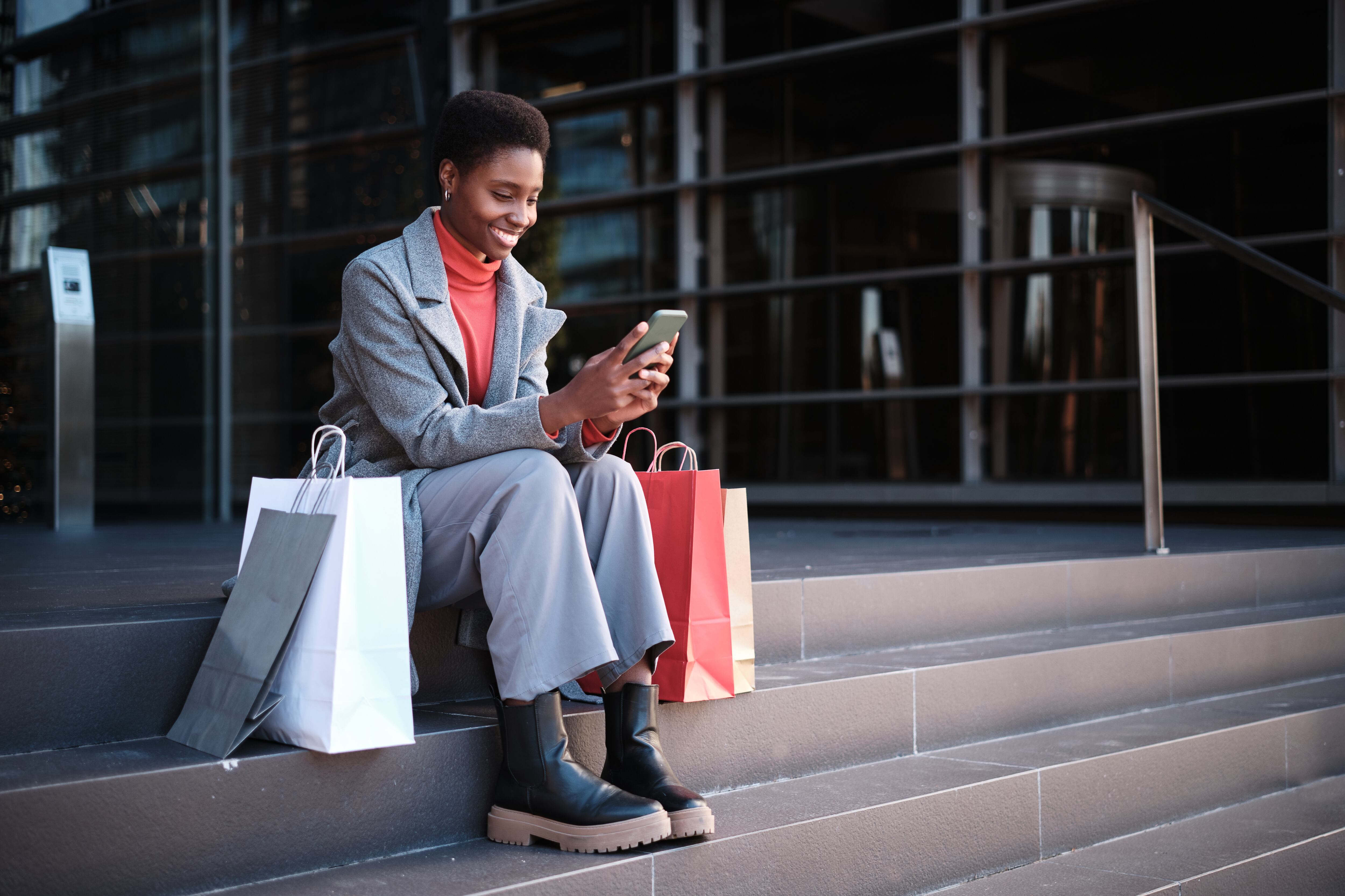 Mujer mirando su móvil tras sus compras.