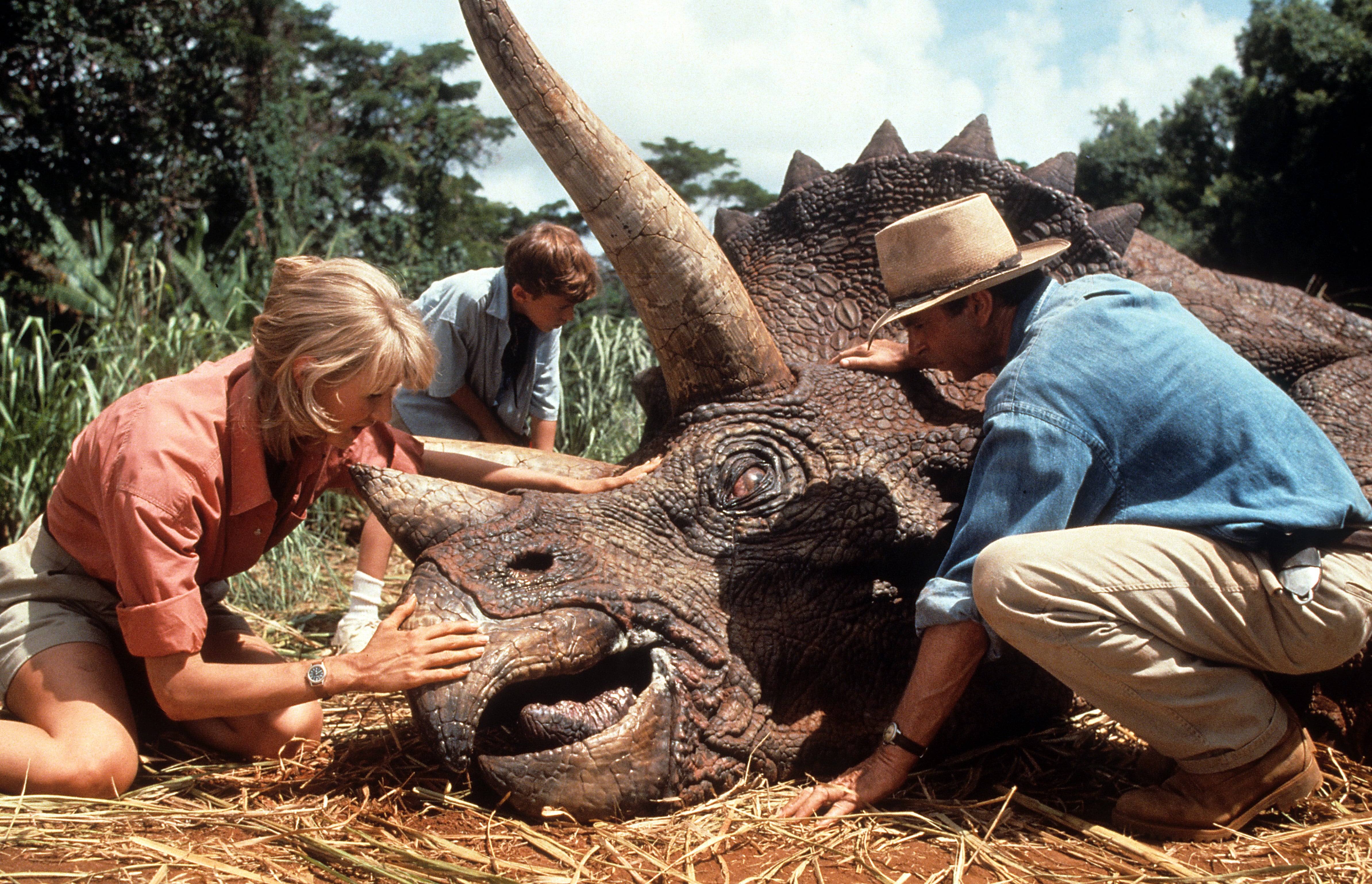 Laura Dern y Sam Neill en la conocida escena del triceratops en 'Parque Jurásico', de 1993. / Universal/Getty