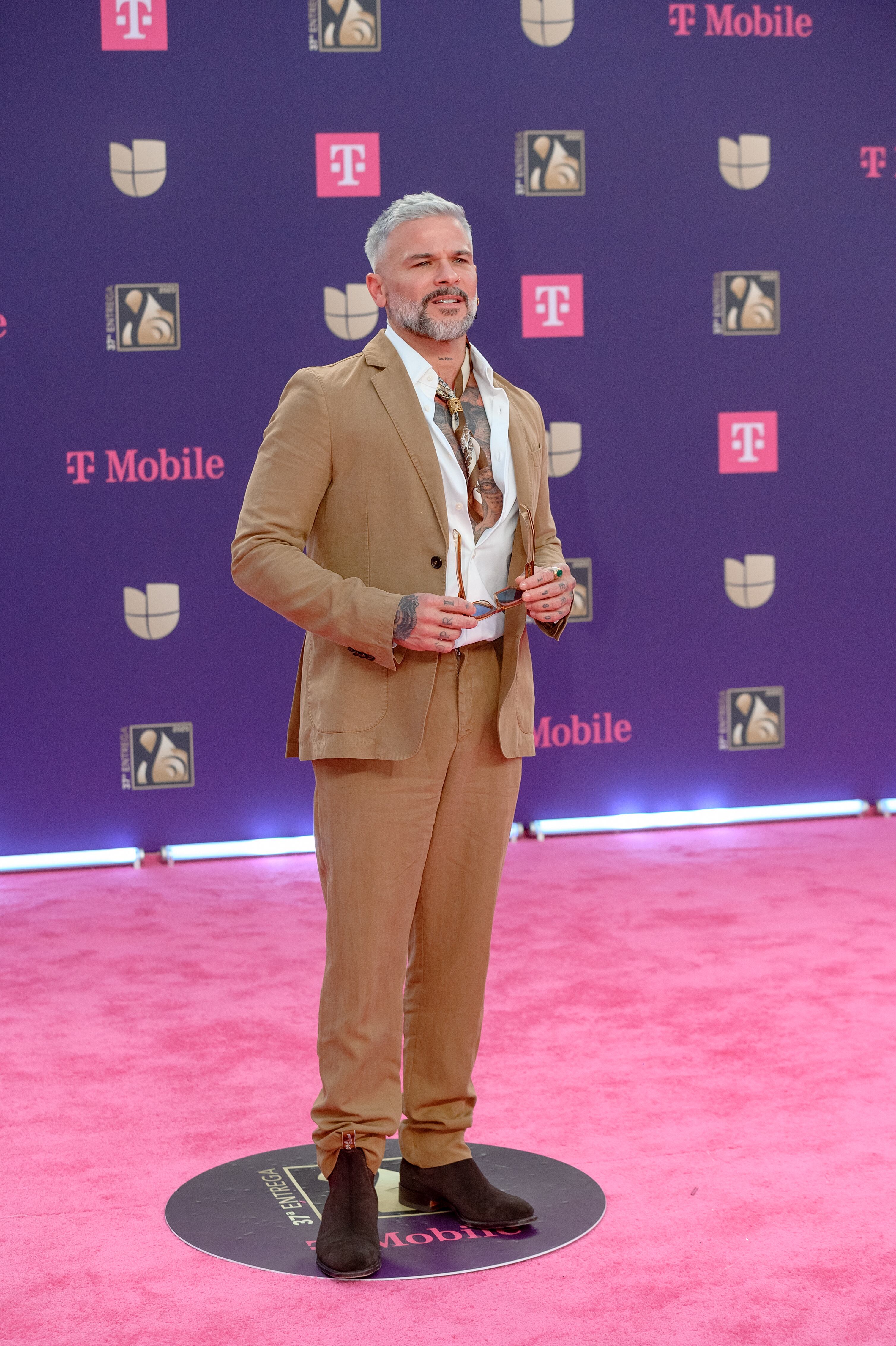 Pedro Capó escogió un color de traje poco usual y un tanto arriesgado para esta alfombra roja. Camisa abierta y pañuelito al cuello para darle su toque.
