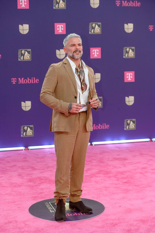Pedro Capó escogió un color de traje poco usual y un tanto arriesgado para esta alfombra roja. Camisa abierta y pañuelito al cuello para darle su toque.