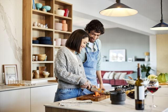 Una pareja preparando una cena romántica en casa.