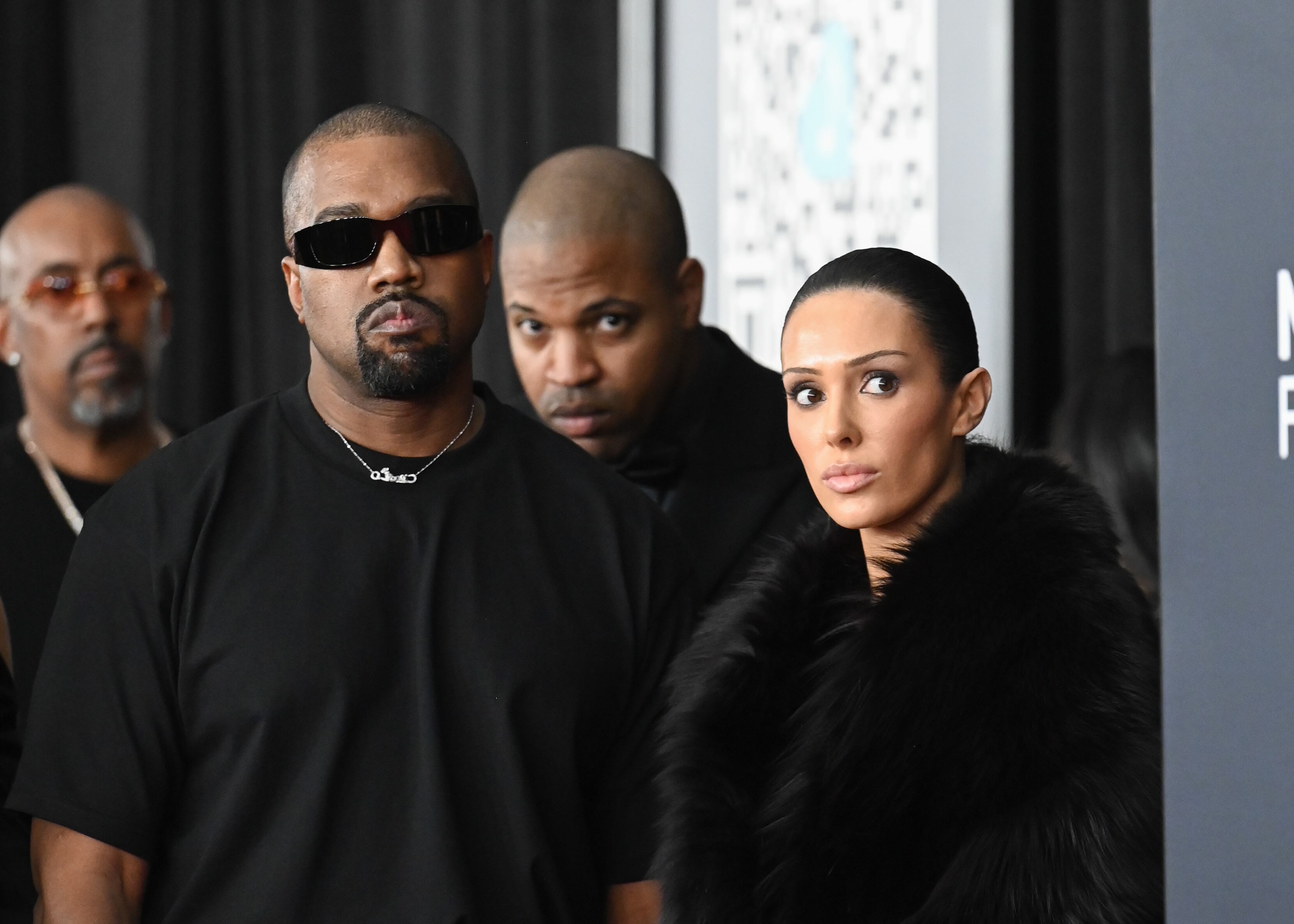 Kanye West, vestido de negro y gafas de solo, y Bianca Censori, con una abrigo grande de pelo, posan en la alfombra roja de la 67ª edición de los premios Grammy en el Crypto.com Arena.