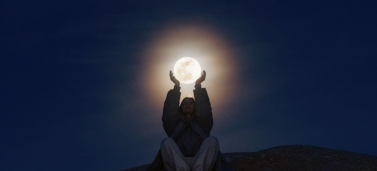 Una joven sosteniendo la luna en sus manos.