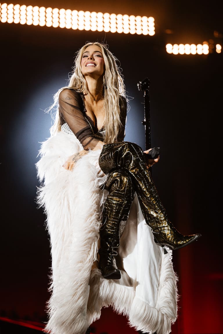 Tini con unas maxi botas efecto piel y una estola extra larga en color blanco.