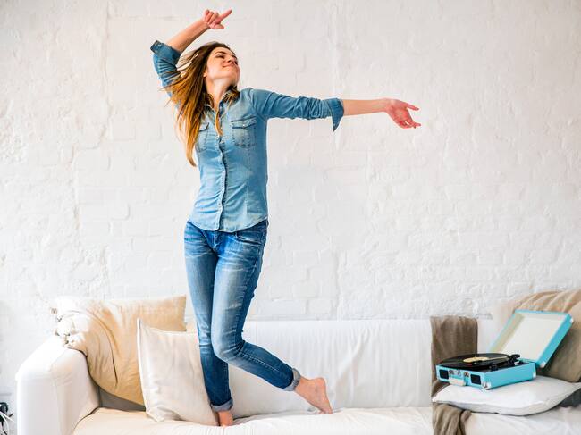 Una joven bailando sobre un sofá