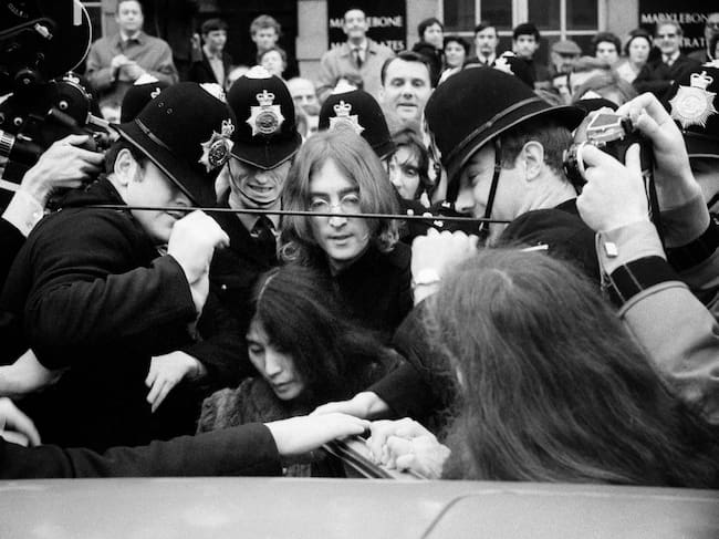 John Lennon y Yoko Ono, protegidos por la policía en la entrada del juzgado (1968).