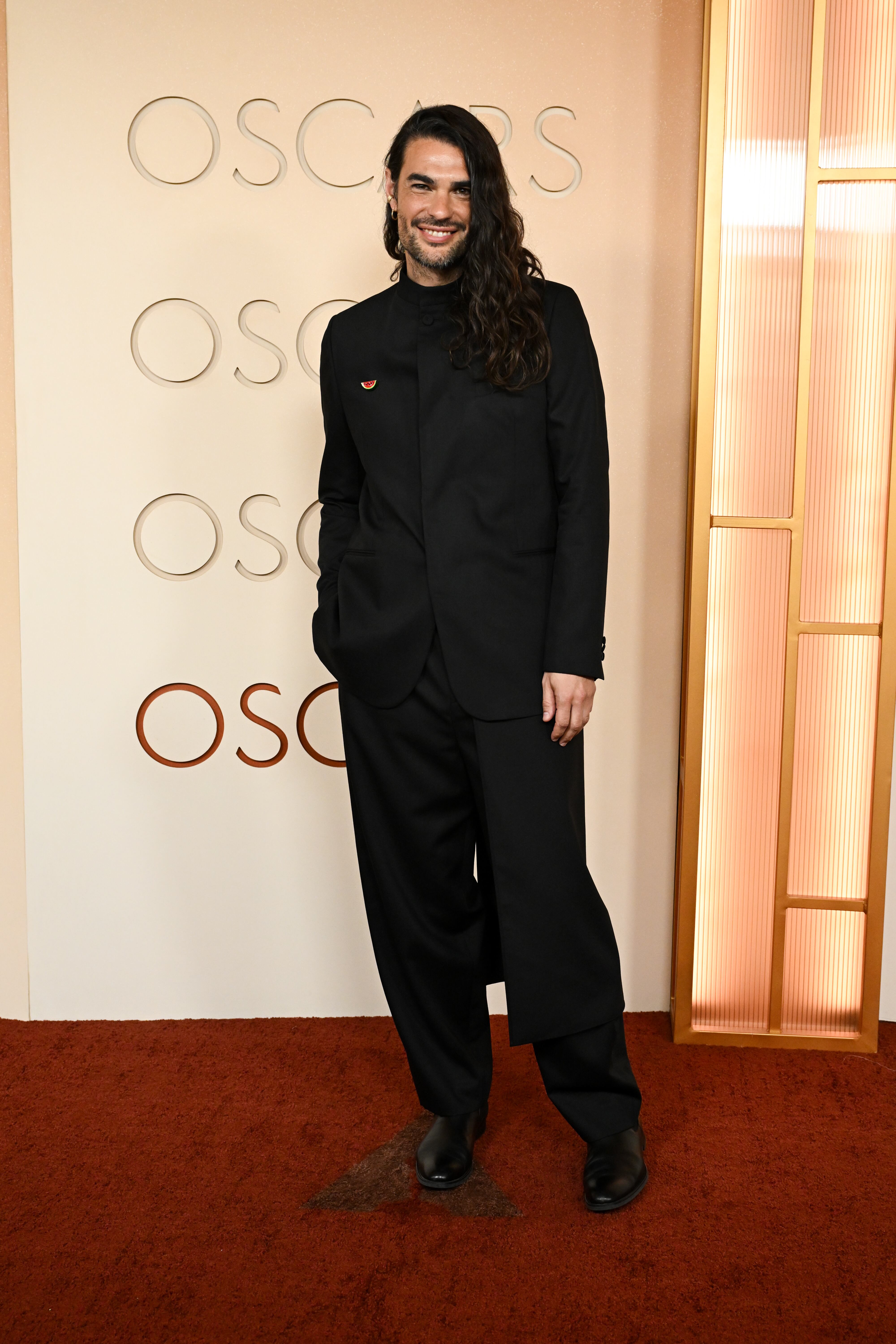 El director español nominado por Sirat ha lucido un traje negro con varias capas y chaqueta con cuello Mao en la que destacaba un pin de apoyo a Palestina.