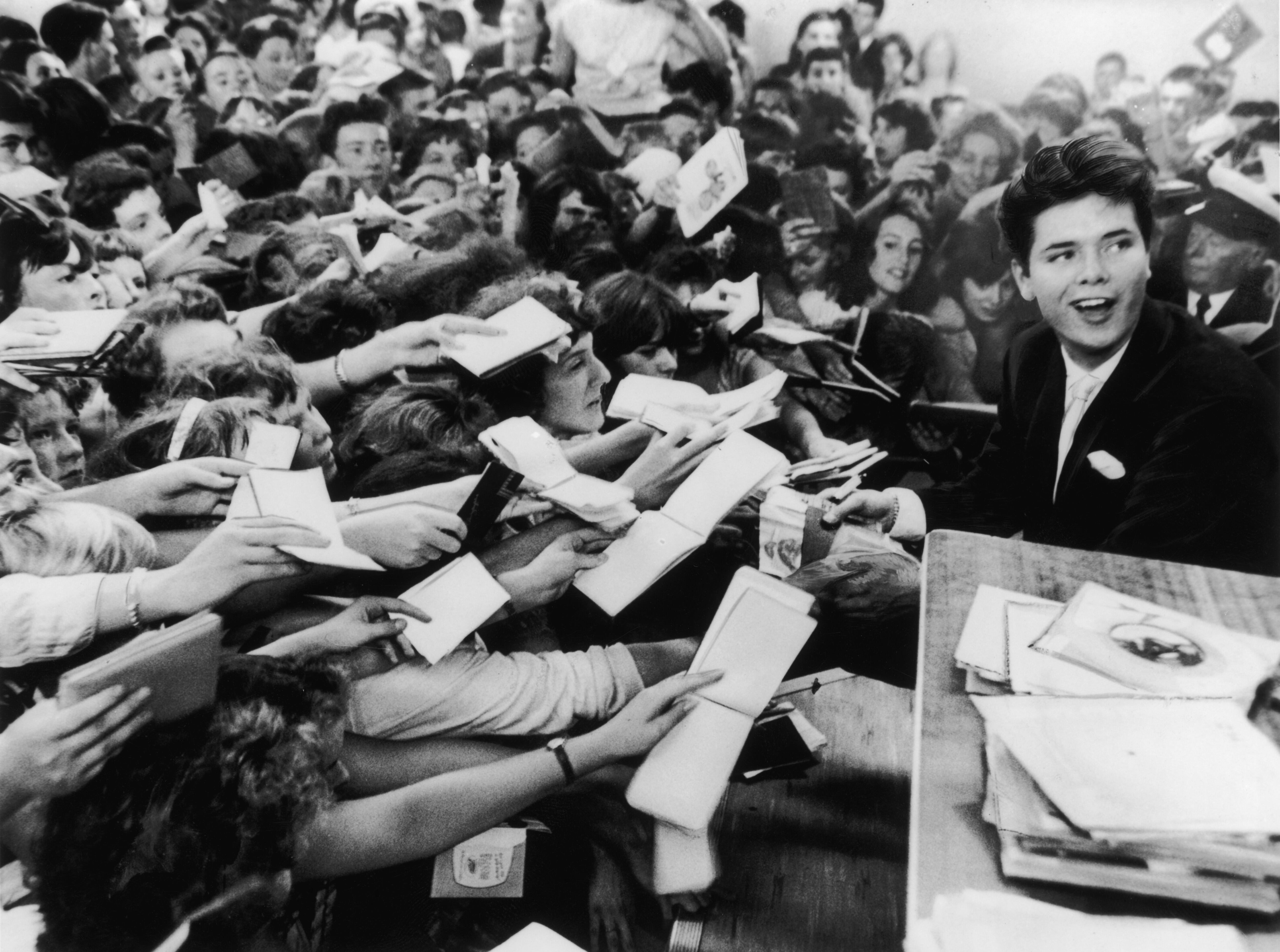 El cantante pop inglés Cliff Richard, de 18 años, es rodeado por sus fans en la Exposición de Niños y Niñas de Hulton, celebrada en el Disc Theatre de Olympia el 19 de agosto de 1959. (Foto de Keystone/Hulton Archive/Getty Images)