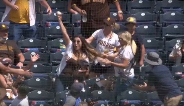 Mujer atrapa pelota de beisbol con bebé en brazos