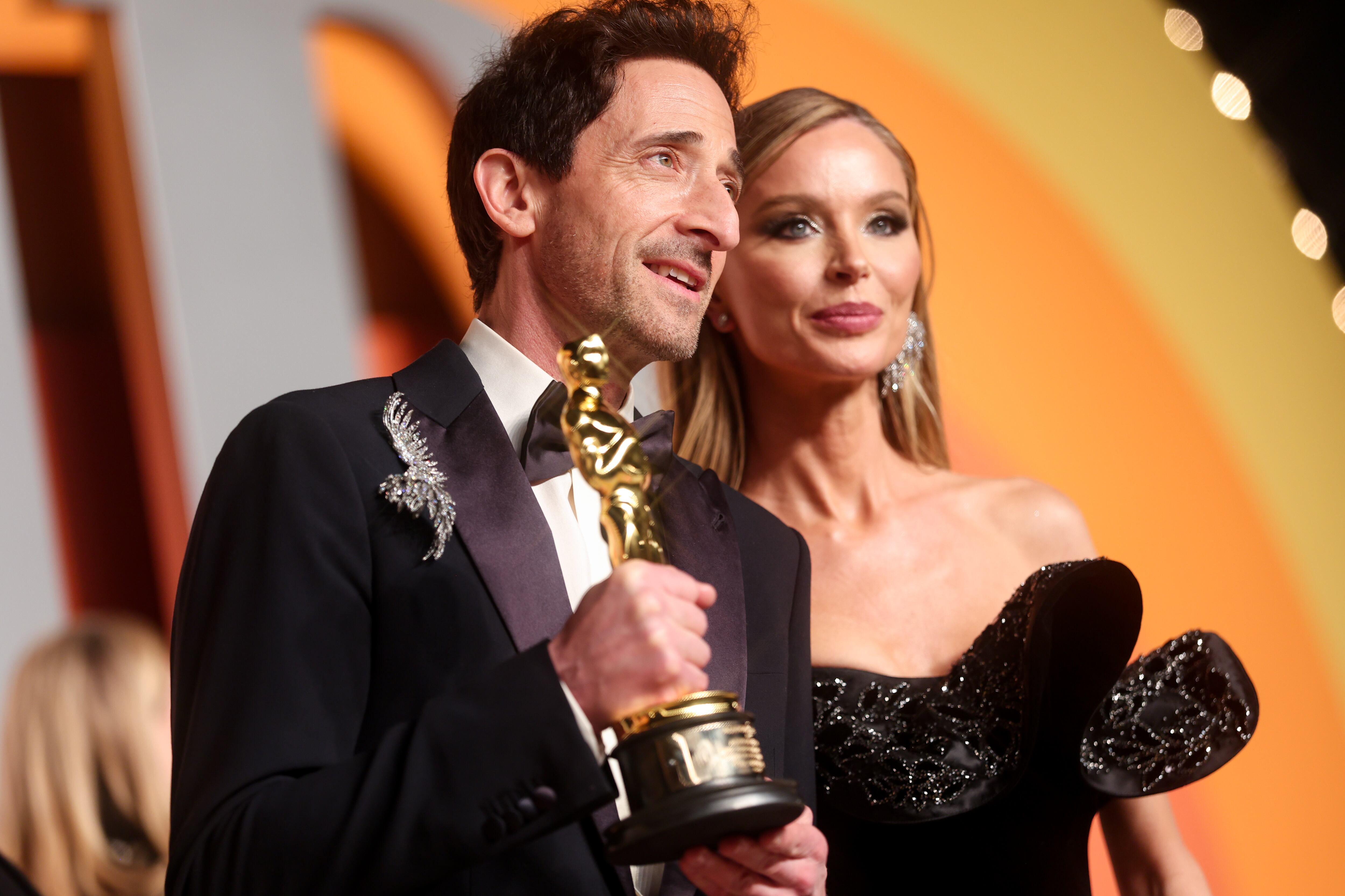 Adrien Brody y su pareja Georgina Chapman, vestidos de gala y posando en la afterparty de Vanity Fair para los Oscars 2025.