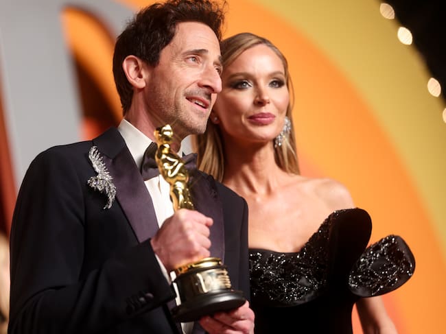 Adrien Brody y su pareja Georgina Chapman, vestidos de gala y posando en la afterparty de Vanity Fair para los Oscars 2025.