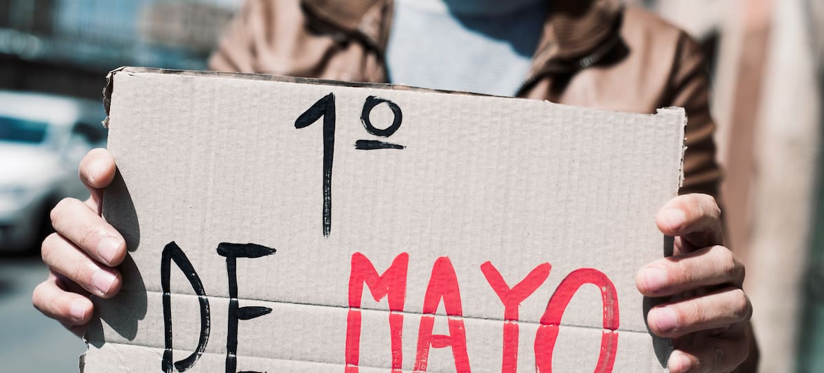 Un hombre posa con un cartel del 1 de mayo