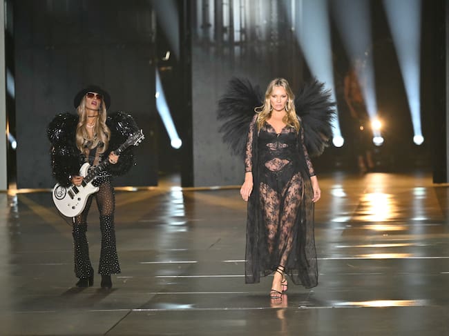 Si hablamos de moda, uno de los nombres más icónicos es el de Kate Moss. Pero, por raro que parezca, nunca había desfilado como ángel, hasta ahora. Con la guitarristat australiana, Orianthi Panagaris, tocando sobre la pasarela, la icónica modelo inauguraba la tercera parte del desfile vestida de encaje negro.