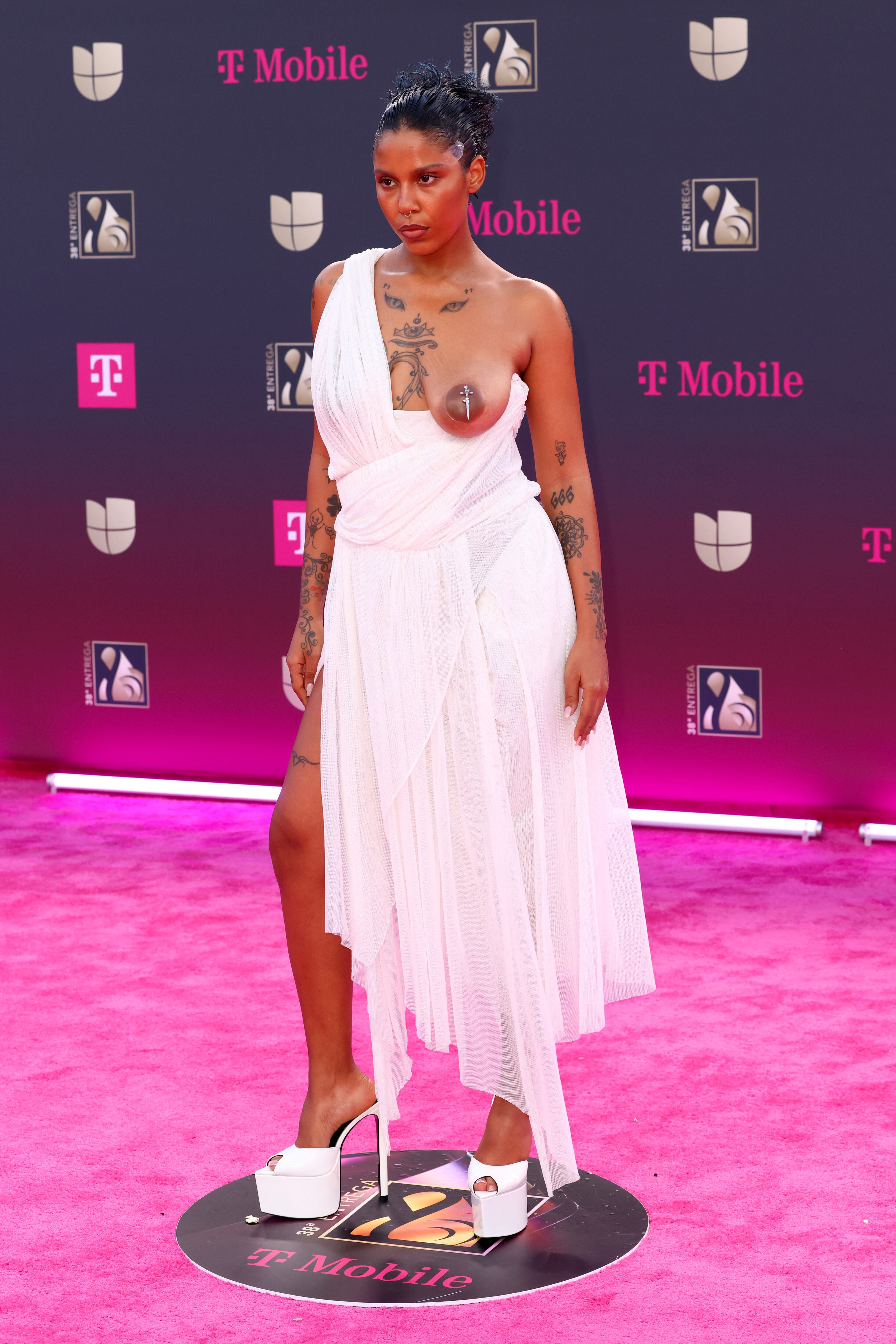 No hay posado en alfombra de Tokischa que no dé qué hablar. En esta ocasión se presentó con un archivo de Vivianne Westwood que dejaba uno de sus pechos al aire. Llevaba mensaje: No voy a operarme las tetas.