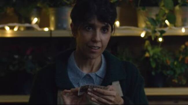 Una joven se sorprende al recoger el décimo premiado que le han dejado encima de su mostrador.