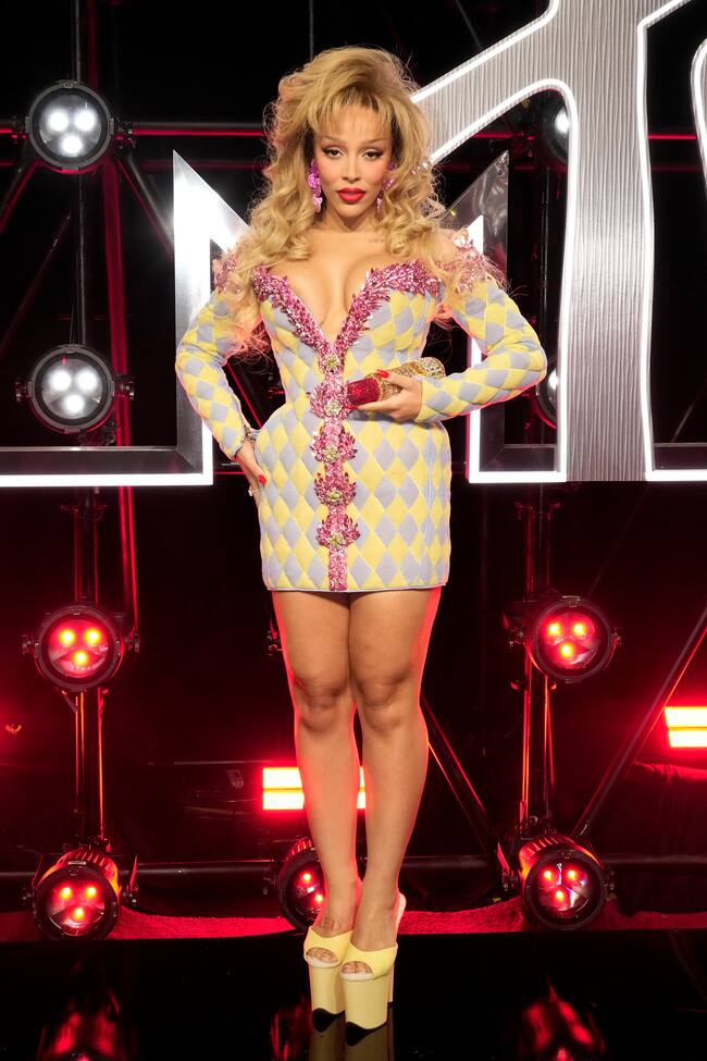 Un cardado ochentero y un Balmain en tonos pastel con sandalias de gran plataforma para Doja Cat que hizo una especie de performance con su pintalabios en la alfombra roja. Primero lo sacó para pintarse los labios y luego se lo comió.