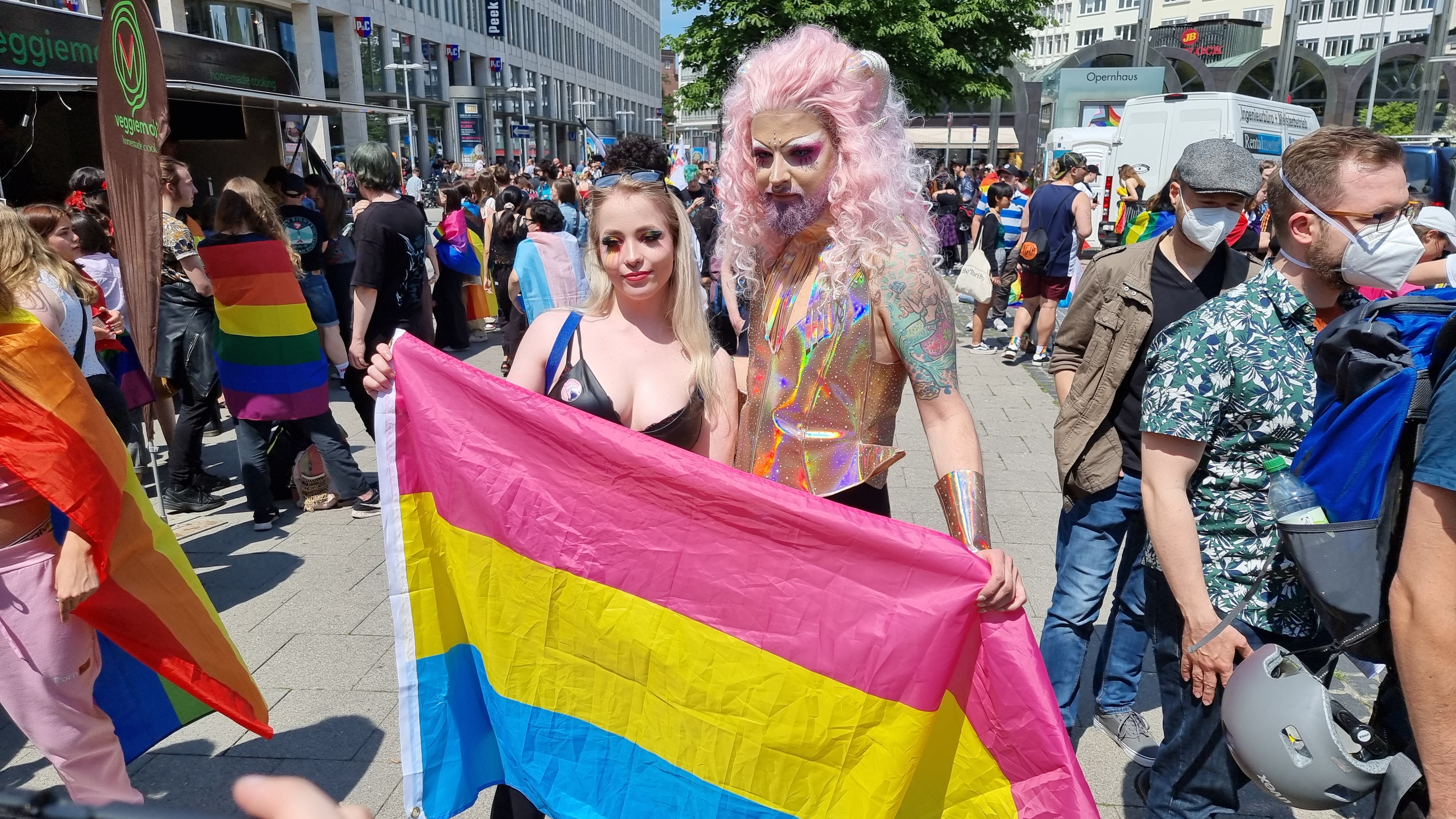 Dos personas en una manifestación LGTBIQ+ sosteniendo la bandera del Orgullo Pansexual.