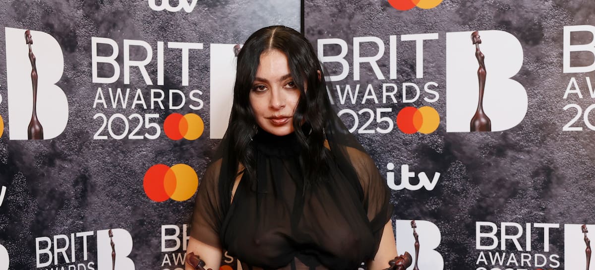 Charli XCX sosteniendo cuatro galardones en el photocall, con un vestido negro y muchas transparencias, de la gala de los BRITS 2025.