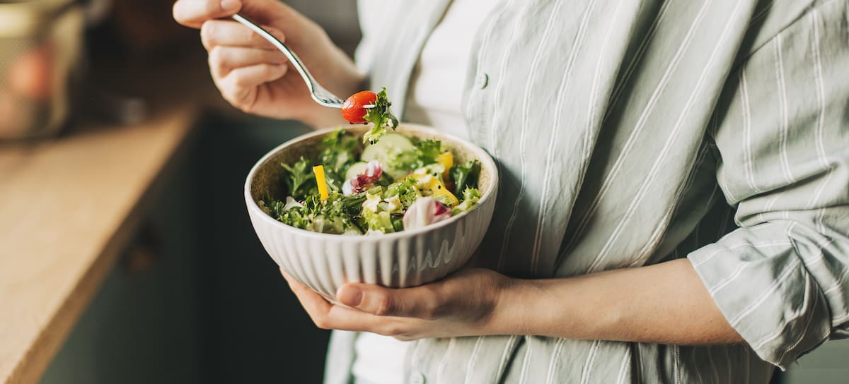Una mujer comiendo una ensalada.