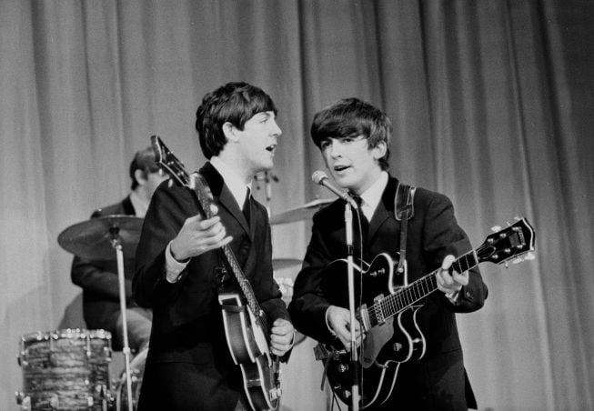 Paul McCartney y George Harrison durante una actuación en 1963.