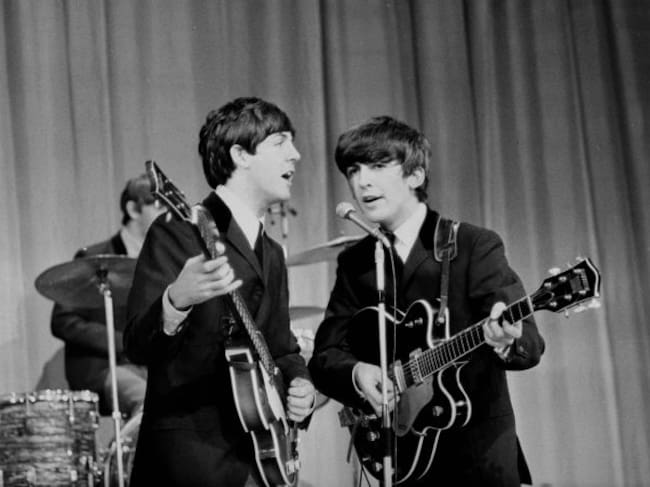 Paul McCartney y George Harrison durante una actuación en 1963.