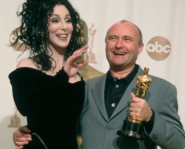 Cher y Phil Collins, que posa con su Oscar.