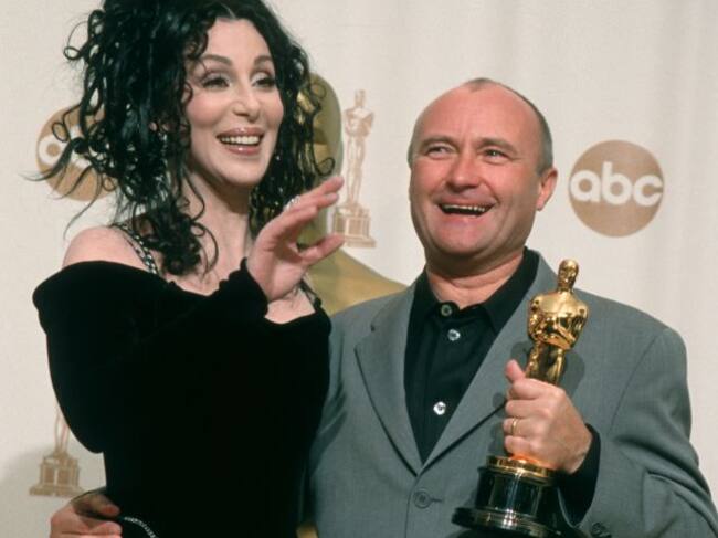 Cher y Phil Collins, que posa con su Oscar.