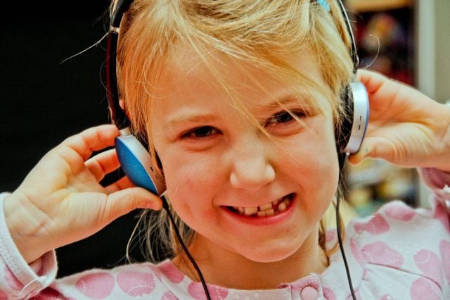 Niña escuchando música con auriculares.