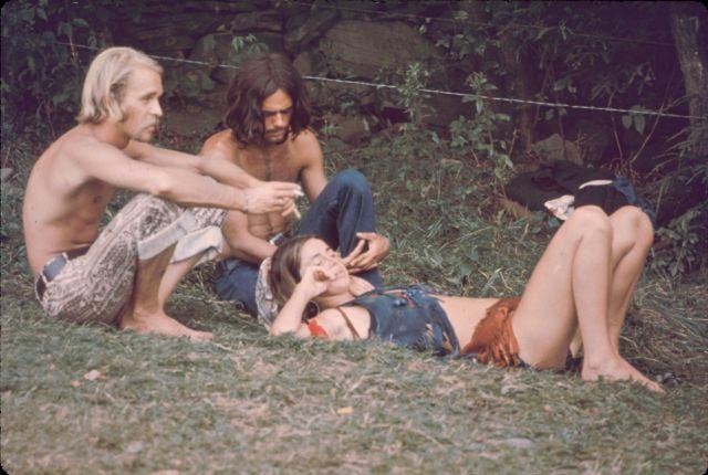 Tres asistentes al festival de Woodstock de 1969, descansando en la hierba.