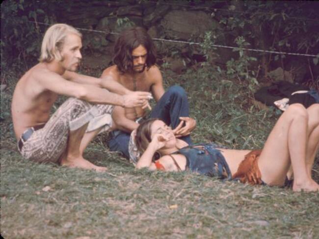 Tres asistentes al festival de Woodstock de 1969, descansando en la hierba.